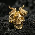 Load image into Gallery viewer, Gold plated demon skull ring with raised broken horns and detailed jawline, macro product-only image on black volcanic rock
