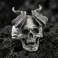 Load image into Gallery viewer, Oxidized sterling silver demon skull ring with cracked ram horns and hollow eye sockets, macro product photo on black volcanic rock
