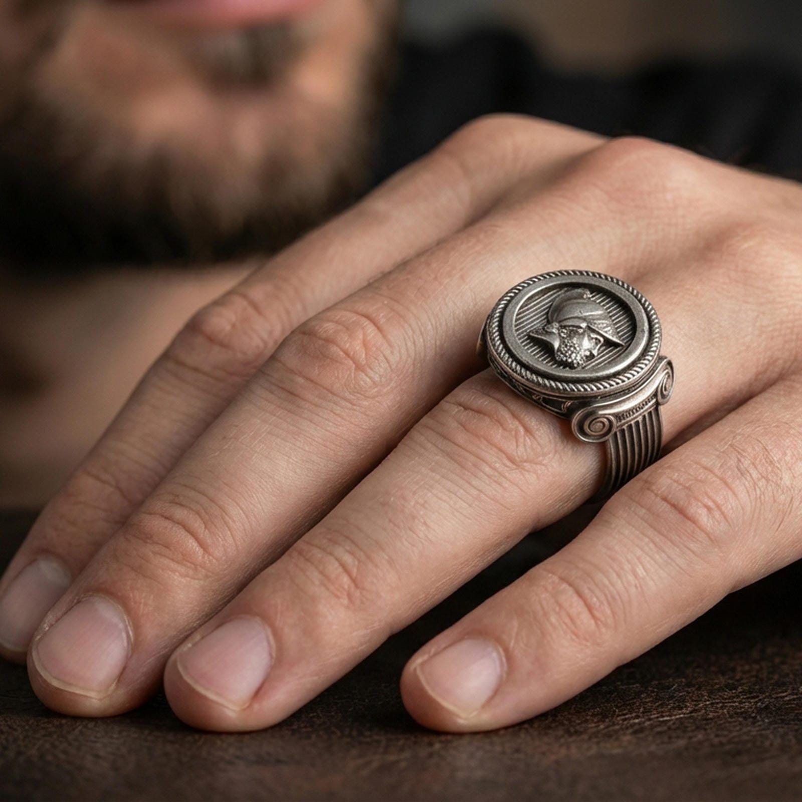 Oxidized Greek coin ring worn on a finger, lifestyle close-up showing the warrior profile relief and rope-edge frame
