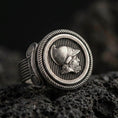 Load image into Gallery viewer, Oxidized sterling silver Greek coin ring with warrior profile relief and rope-edge frame, macro product photo on black volcanic rock
