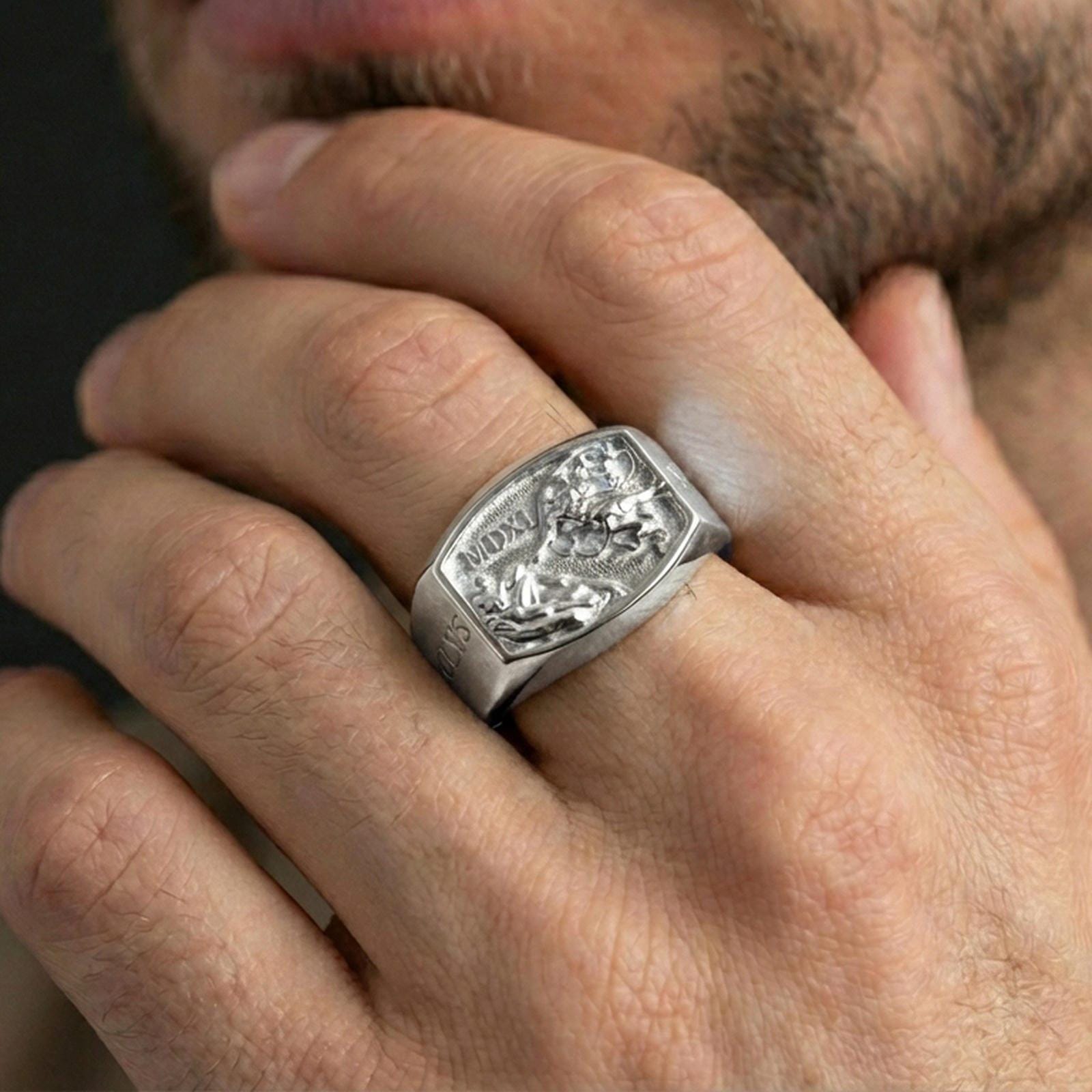 Polished silver Saint Michael ring on the finger, wearable photo emphasizing the sculpted relief scene and crisp engraving