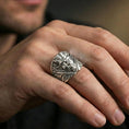 Load image into Gallery viewer, Polished silver demon face ring on the finger, wearable photo focusing on the sculpted facial expression and ornate side accents
