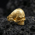 Load image into Gallery viewer, Gold plated skull ring with detailed baroque scrollwork pattern and high-relief engraving, product-only macro image on black volcanic rock
