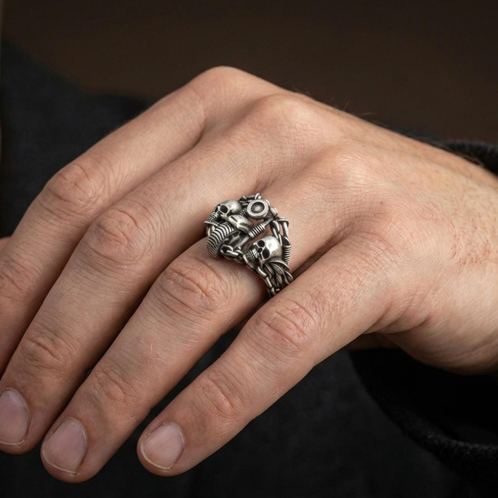 Oxidized double skull motorcycle ring worn on a finger, lifestyle close-up highlighting the handlebar motif and chain texture