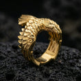 Load image into Gallery viewer, Gold plated eagle wing open band ring with raised feather scales and carved bird head detail, product-only macro image on black volcanic rock
