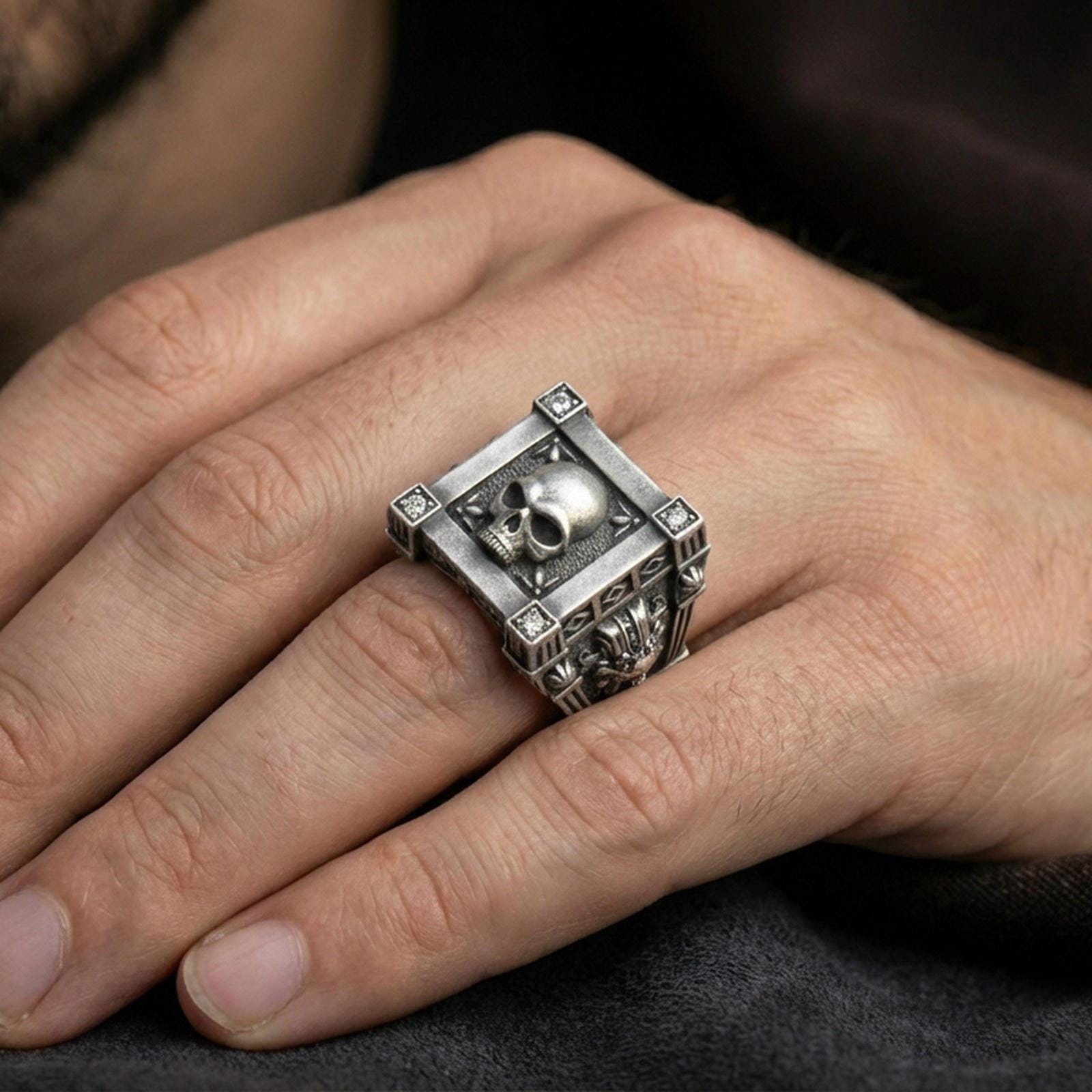 Oxidized framed skull ring worn on a finger, lifestyle close-up showing lab diamond corner accents and bold gothic styling