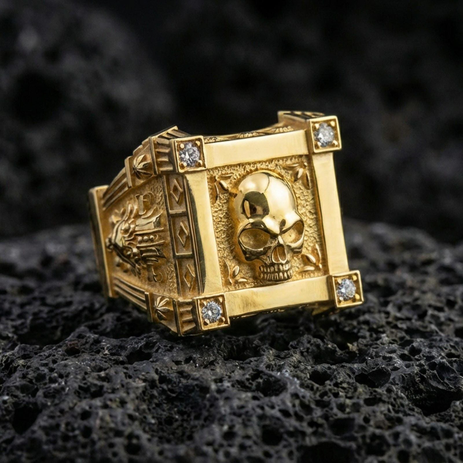 Gold plated skull ring with framed skull face and lab diamond accents on the corners, product-only macro image on volcanic rock