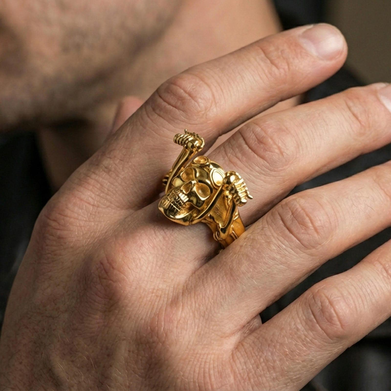 Gold plated biker skull ring worn on a finger, close-up lifestyle image emphasizing the goggles and skeletal arm design