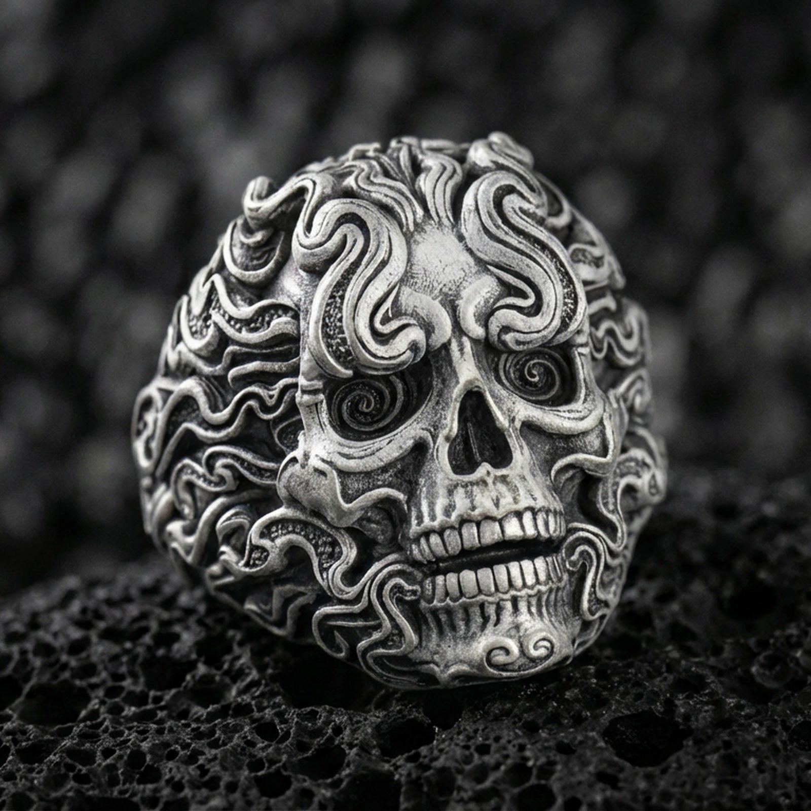 Oxidized sterling silver smoke skull ring with swirling flame-like curls and spiral eyes, macro photo on black volcanic rock