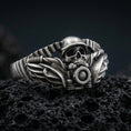 Load image into Gallery viewer, Oxidized sterling silver biker skull ring with winged details and motorcycle handlebar motif, macro photo on black volcanic rock
