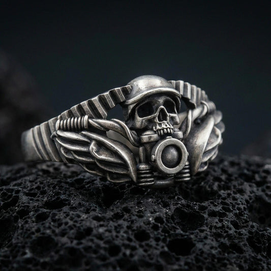 Oxidized sterling silver biker skull ring with winged details and motorcycle handlebar motif, macro photo on black volcanic rock