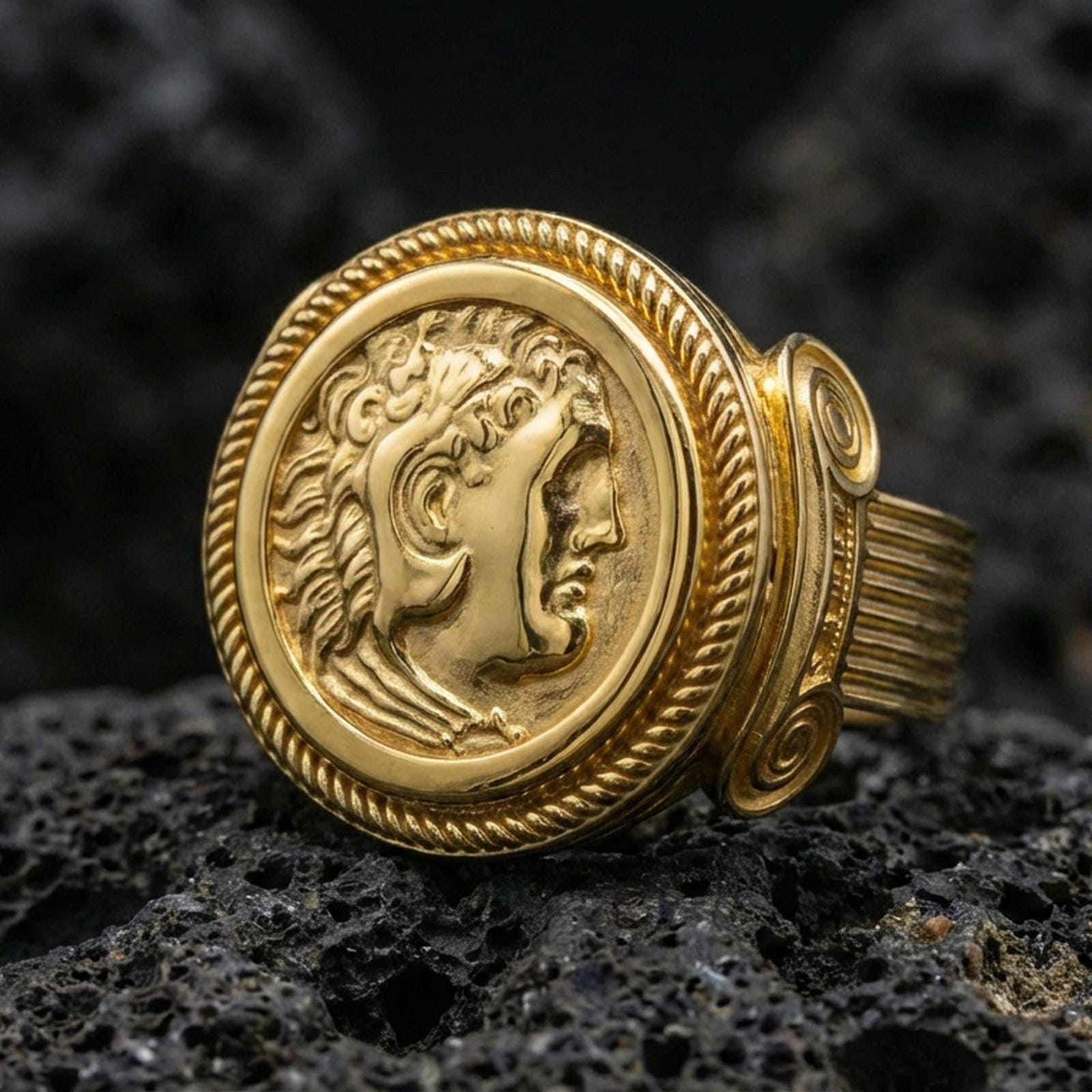 Gold plated Greek coin ring with classical profile portrait and rope edge bezel, product-only macro on black volcanic rock