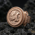 Load image into Gallery viewer, Rose gold plated ancient coin ring with detailed classical portrait and rope border bezel, close-up on volcanic rock
