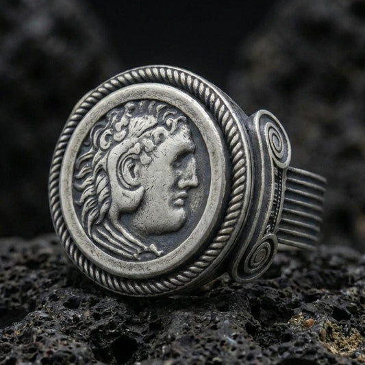 Oxidized sterling silver Greek coin ring featuring a classical profile portrait framed by a rope border, macro photo on black volcanic rock