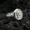 Load image into Gallery viewer, Polished silver ancient Roman coin signet ring with Augustus portrait relief and engraved Latin text, close-up on volcanic stone
