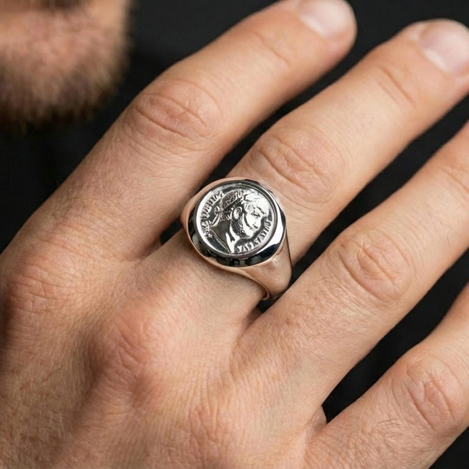 Polished silver Augustus coin signet ring on the finger, wearable close-up focusing on the raised portrait relief and coin edge