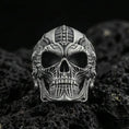 Load image into Gallery viewer, Oxidized sterling silver biomechanical skull ring with futuristic engraved lines and deep relief, macro photo on black volcanic rock
