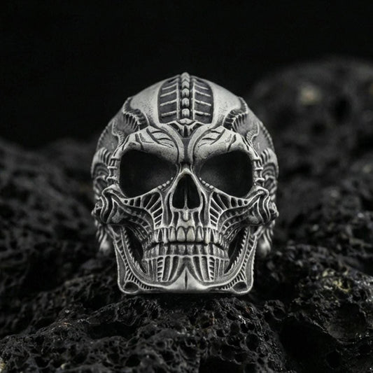 Oxidized sterling silver biomechanical skull ring with futuristic engraved lines and deep relief, macro photo on black volcanic rock