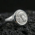 Load image into Gallery viewer, Polished silver coin portrait signet ring featuring a crowned bearded profile and raised round bezel, close-up on volcanic stone
