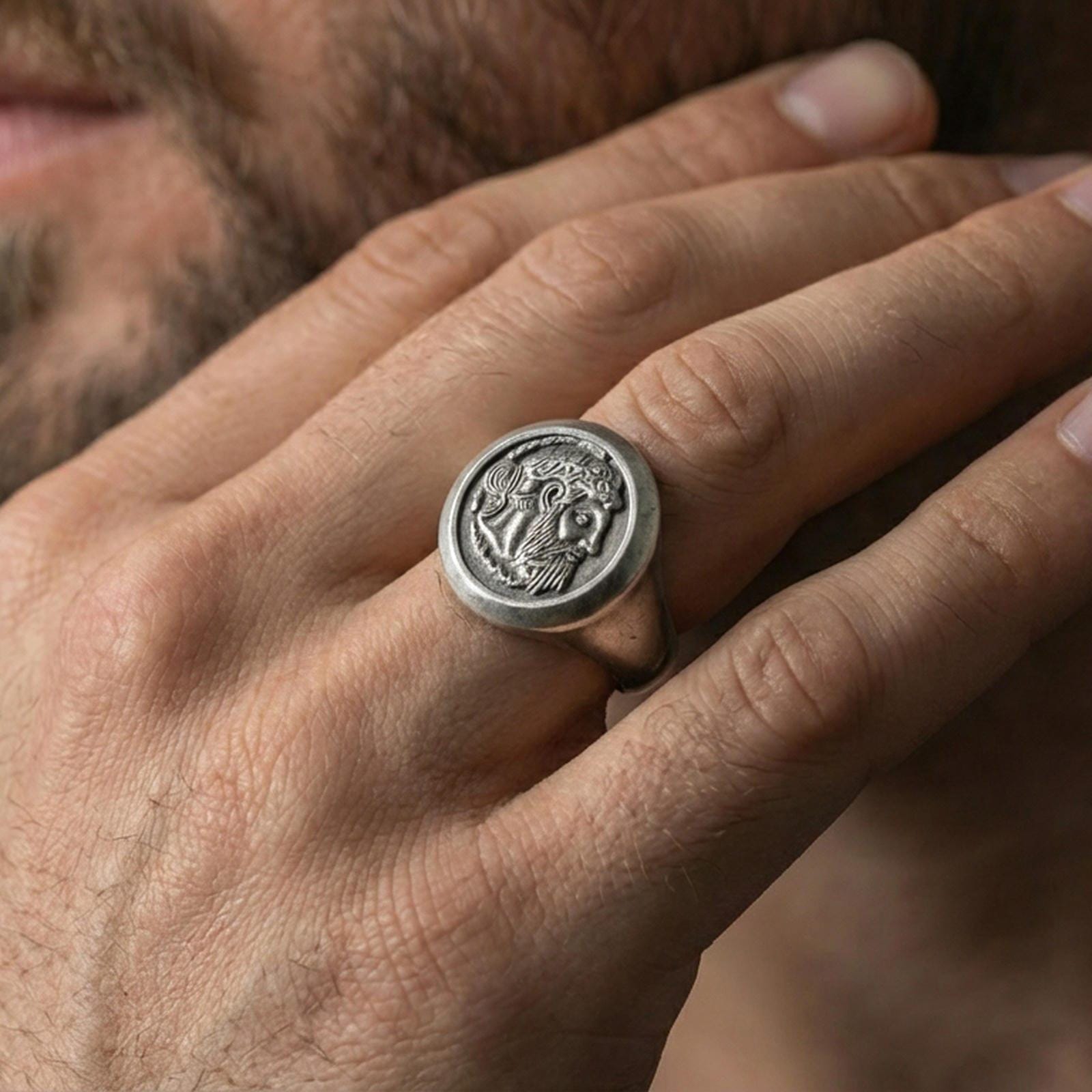 Oxidized coin portrait signet ring worn on a finger, close-up lifestyle shot highlighting the bearded ruler relief