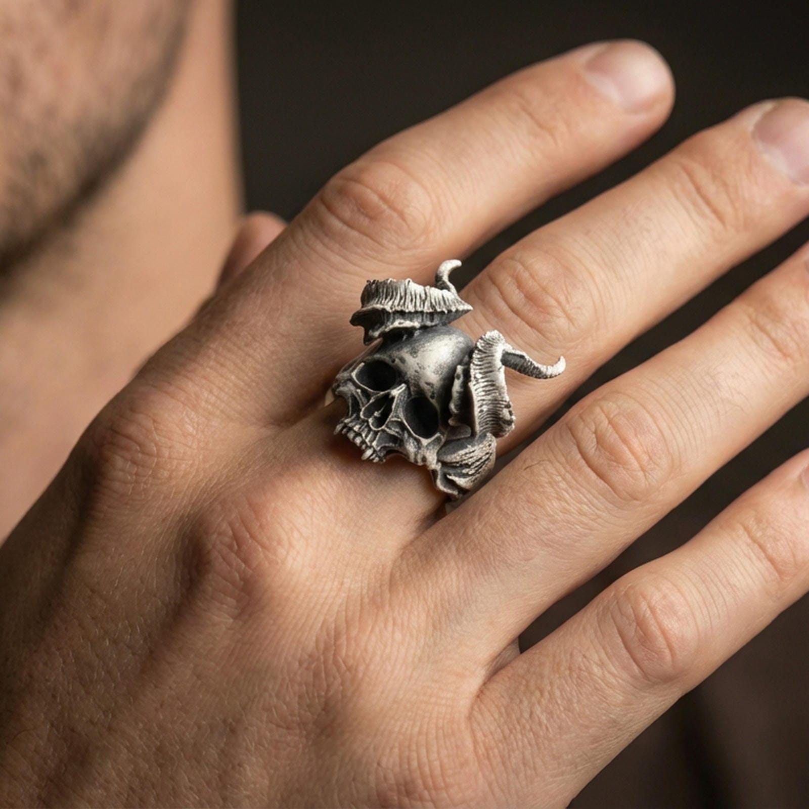 Oxidized horned skull ring worn on a finger, close-up lifestyle shot highlighting the curved horns and skull relief