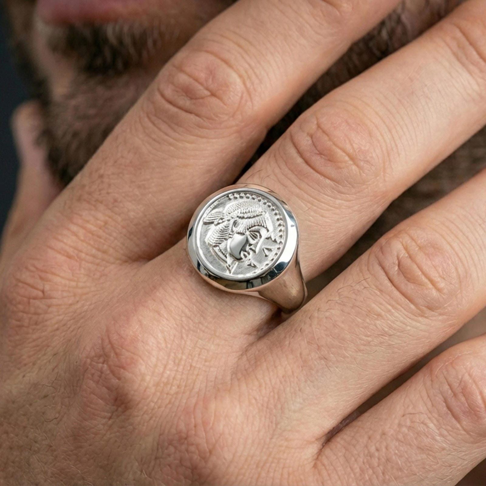 Polished silver Greek coin ring on the finger, wearable close-up focusing on the raised classical profile and signet shape