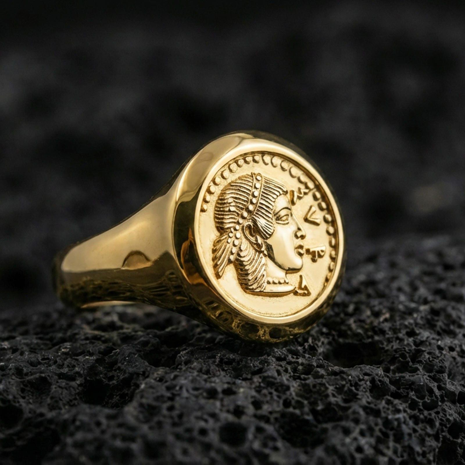 Gold plated Greek coin signet ring with an ancient-style lady profile and beaded rim detail, product-only macro on black volcanic rock