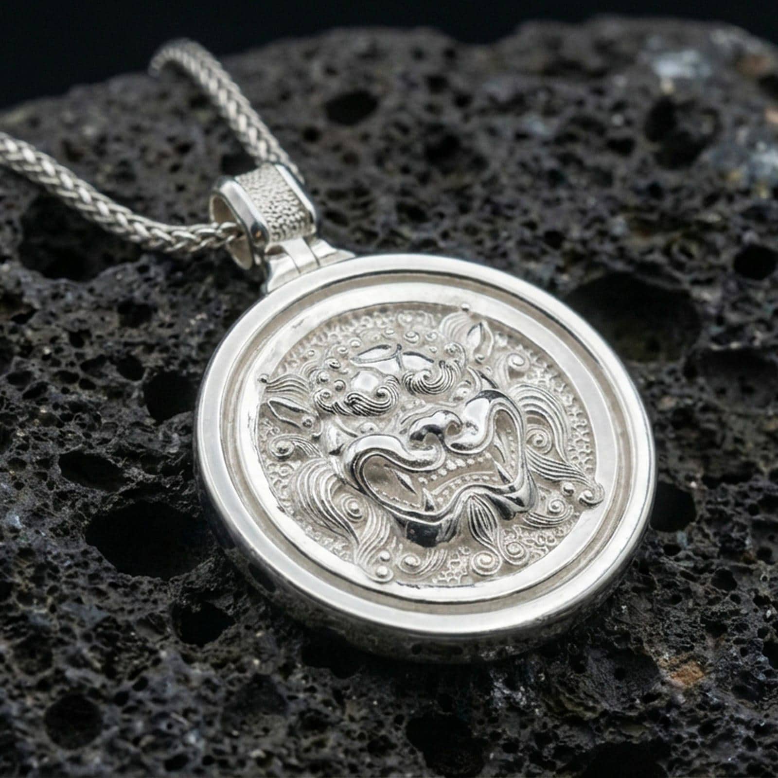 Polished silver guardian lion medallion necklace on volcanic rock, crisp relief detail and smooth bezel frame, close-up