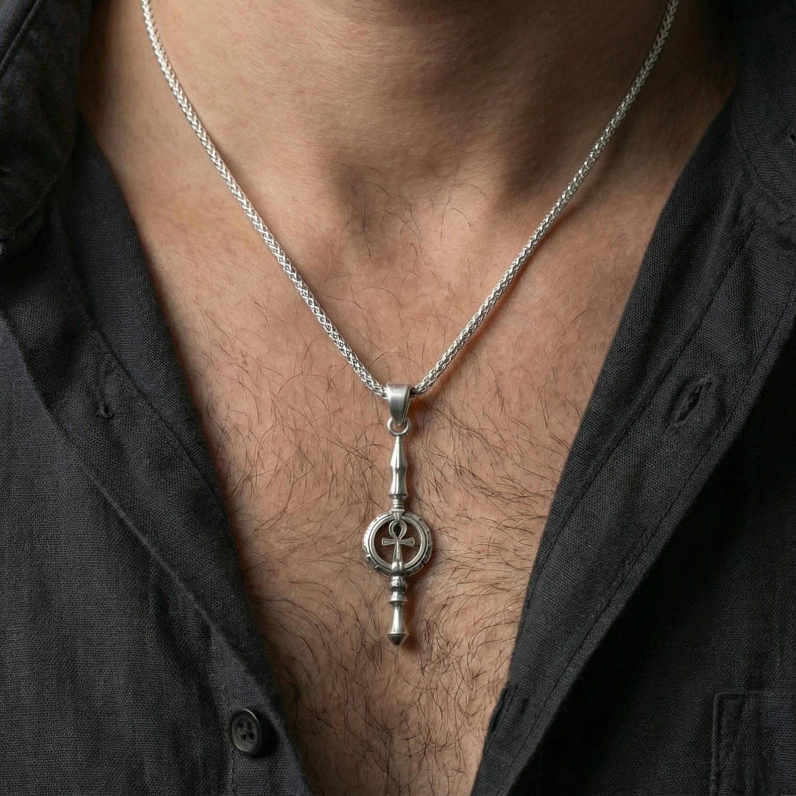 Polished silver ankh spear necklace worn on neck, minimal lifestyle framing, crisp shine and sculpted edges