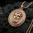 Load image into Gallery viewer, Rose gold plated Medusa medallion pendant on volcanic rock, textured lava stone background, high-detail antique relief
