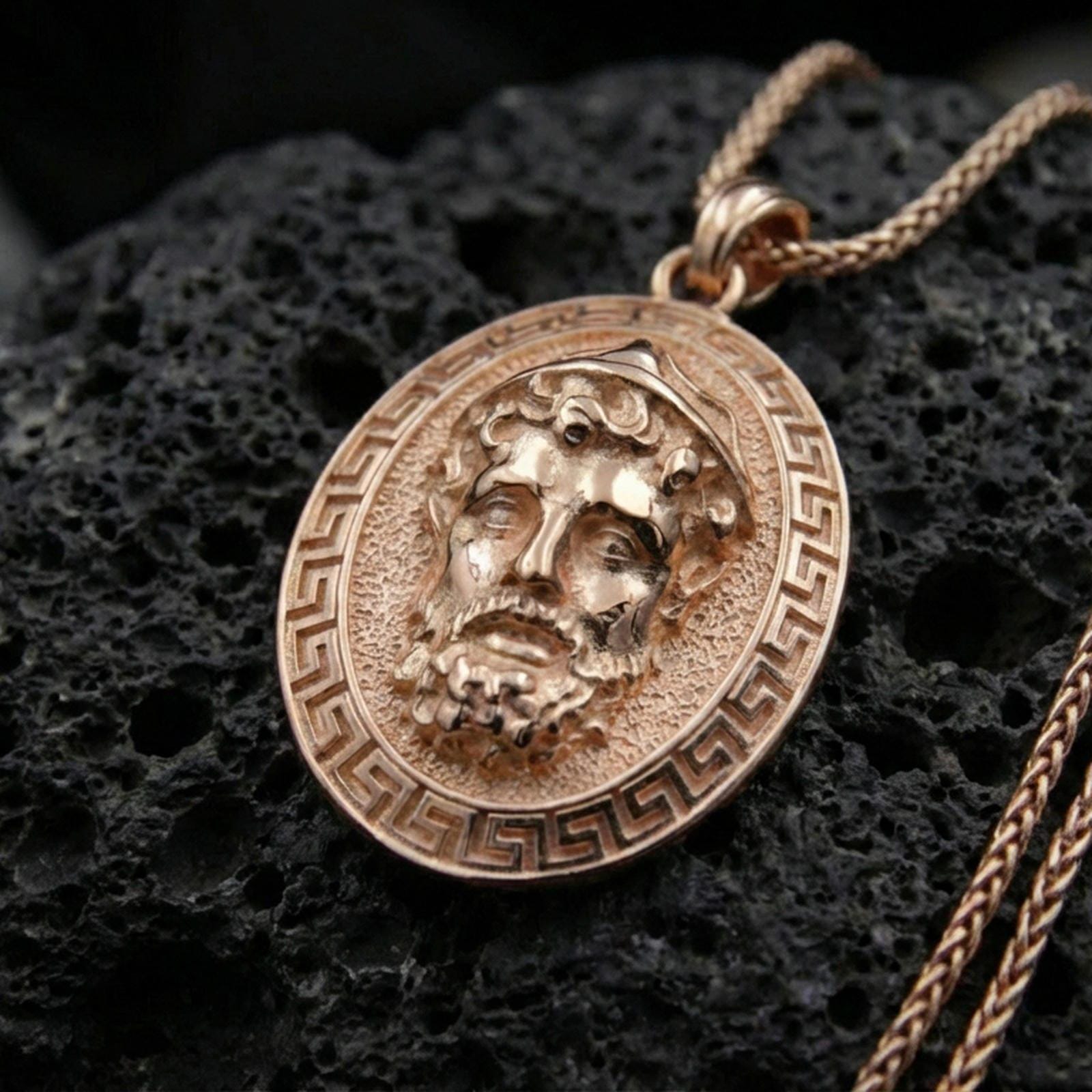 Rose gold plated Medusa medallion pendant on volcanic rock, textured lava stone background, high-detail antique relief