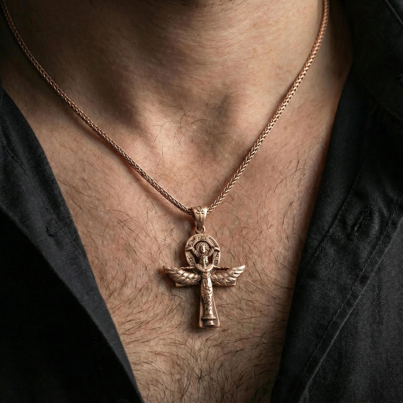 Rose gold plated winged ankh cross necklace worn on neck, lifestyle wear shot, warm plating tone and sculpted depth