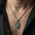 Load image into Gallery viewer, Oxidized phoenix bird pendant necklace worn on neck, lifestyle close-up, oval medallion centered with braided chain
