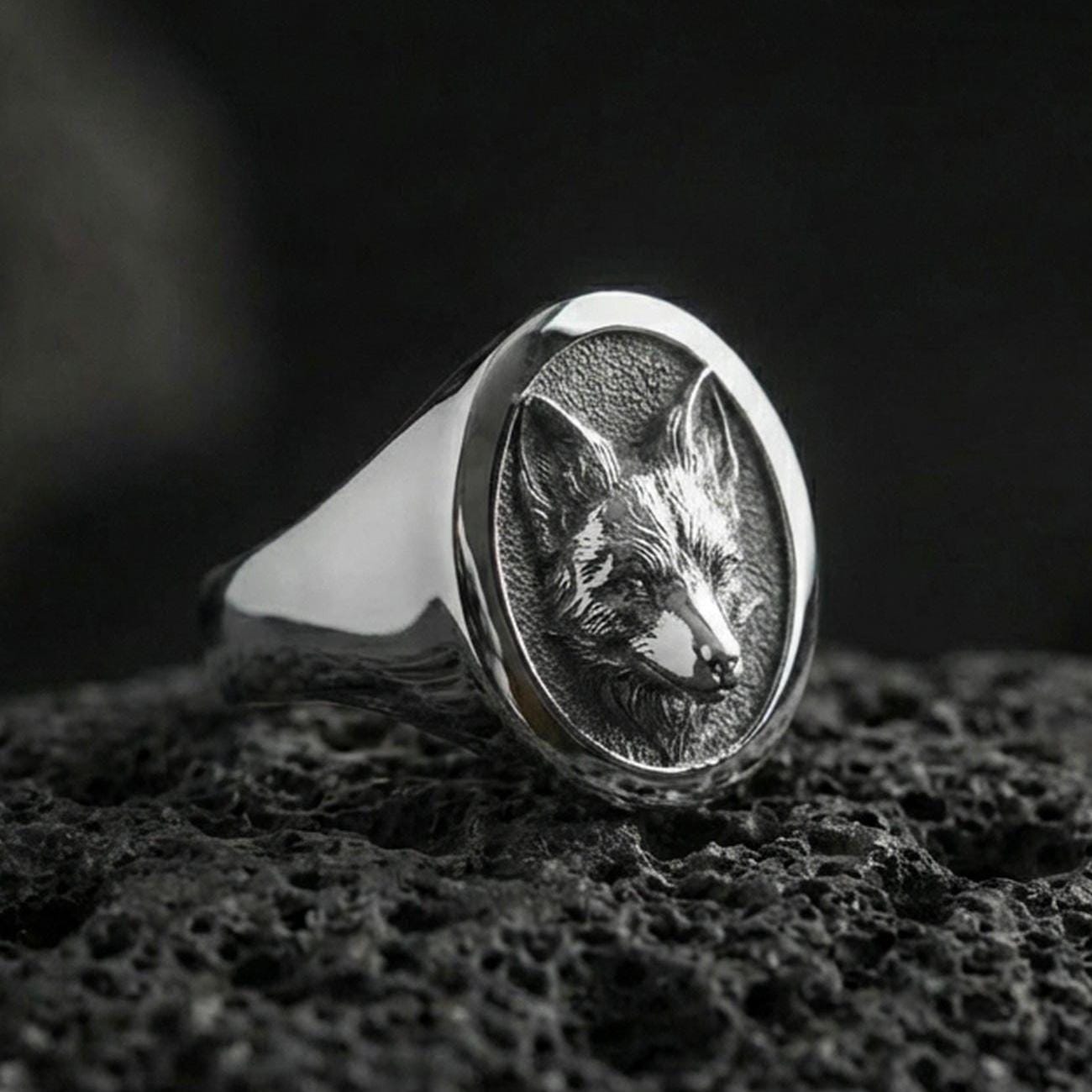 Polished silver fox head signet ring on volcanic rock, crisp sculpted ears and muzzle, clean bezel edge close-up
