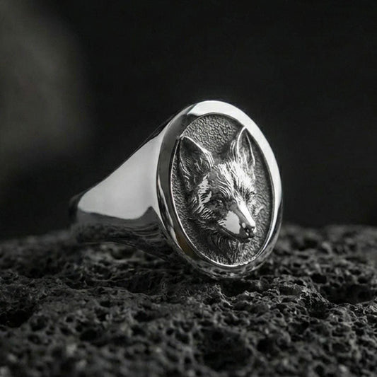 Polished silver fox head signet ring on volcanic rock, crisp sculpted ears and muzzle, clean bezel edge close-up