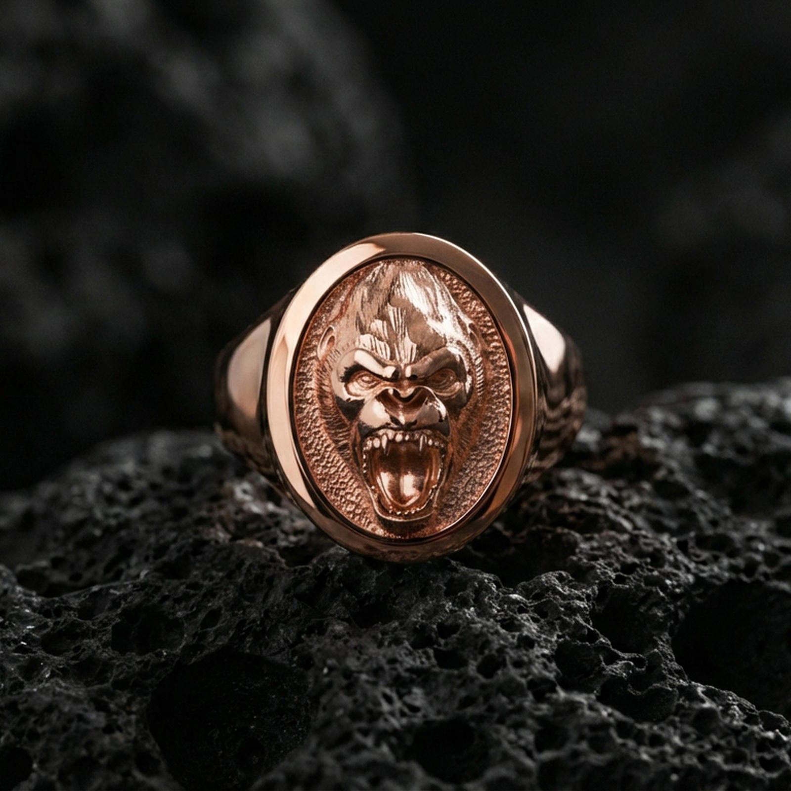 Rose gold plated gorilla head signet ring on volcanic rock, textured lava stone background, detailed roar expression engraving