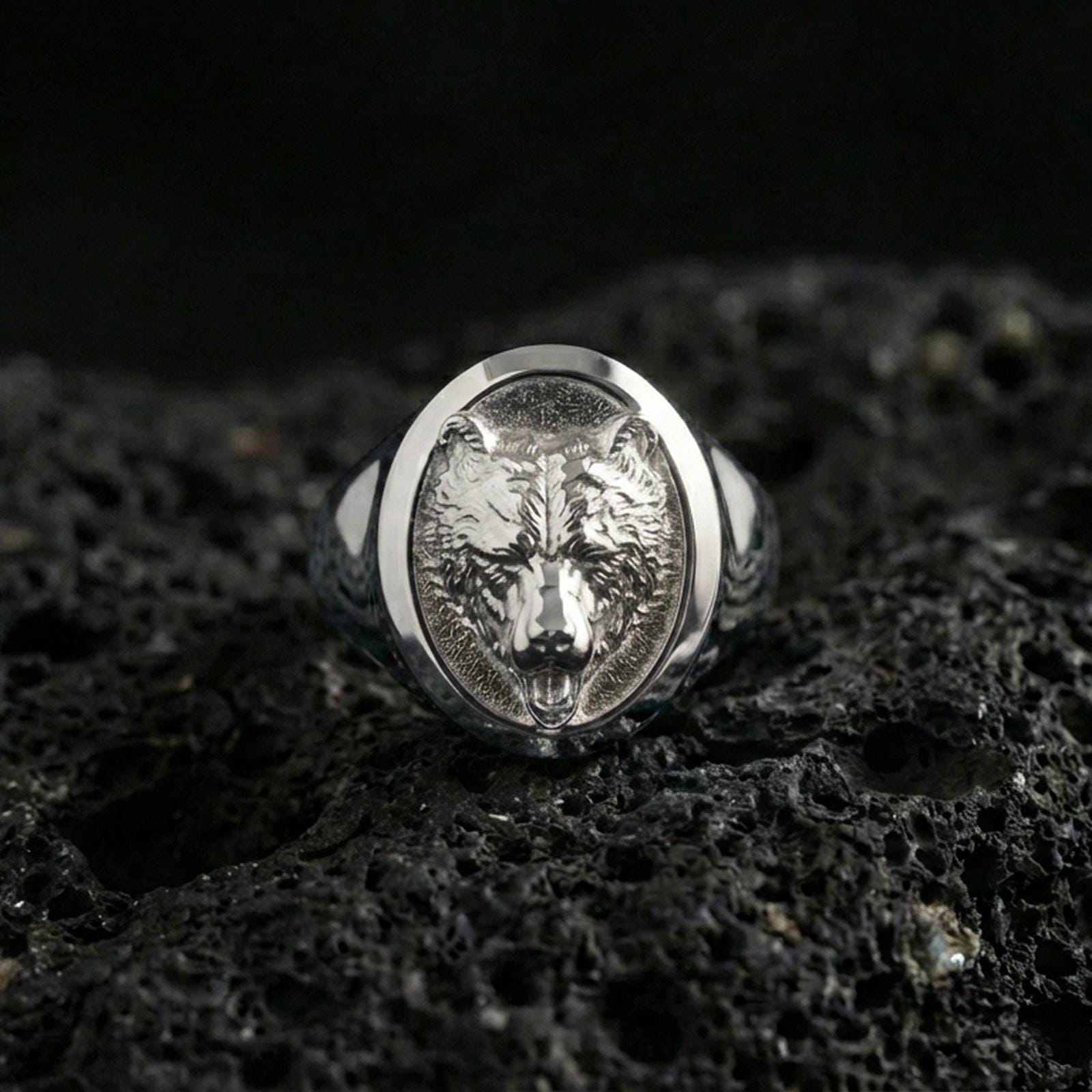 Polished silver bear signet ring on volcanic rock, crisp facial contours and smooth oval bezel edge, close-up lighting
