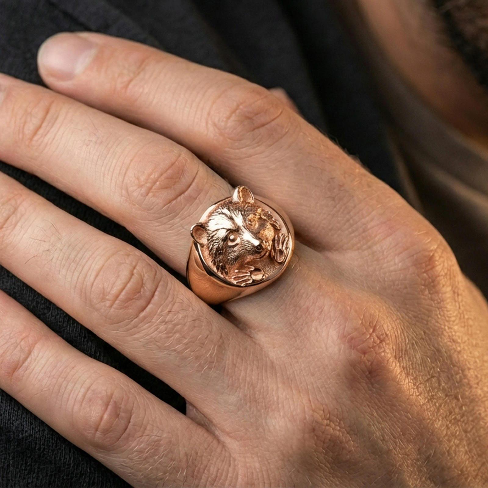 Rose gold plated raccoon signet ring worn on finger, lifestyle wear shot, warm plating tone and sculpted depth