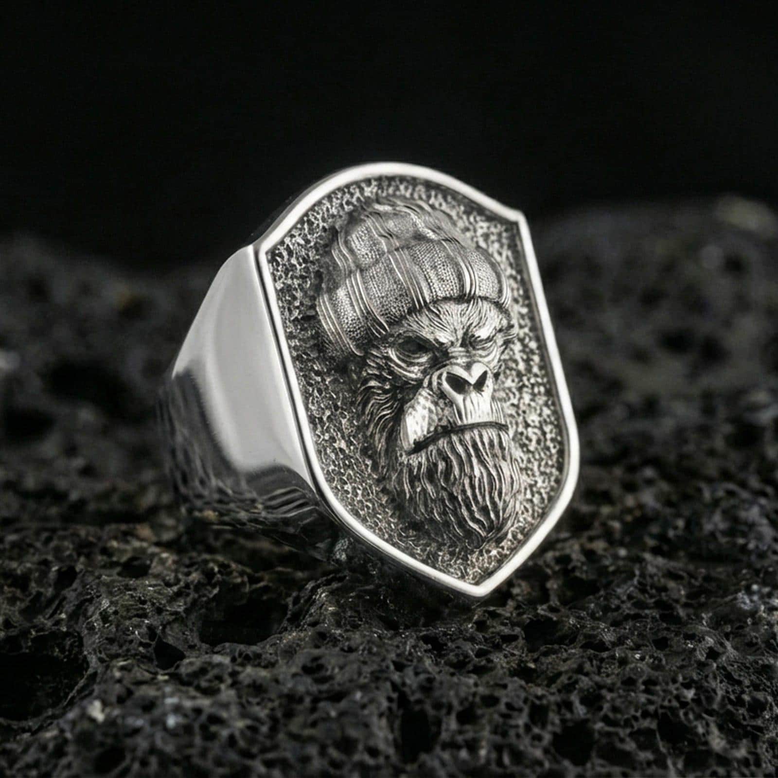 Polished silver gorilla warrior signet ring on volcanic rock, crisp beard and helmet relief, clean shield bezel close-up