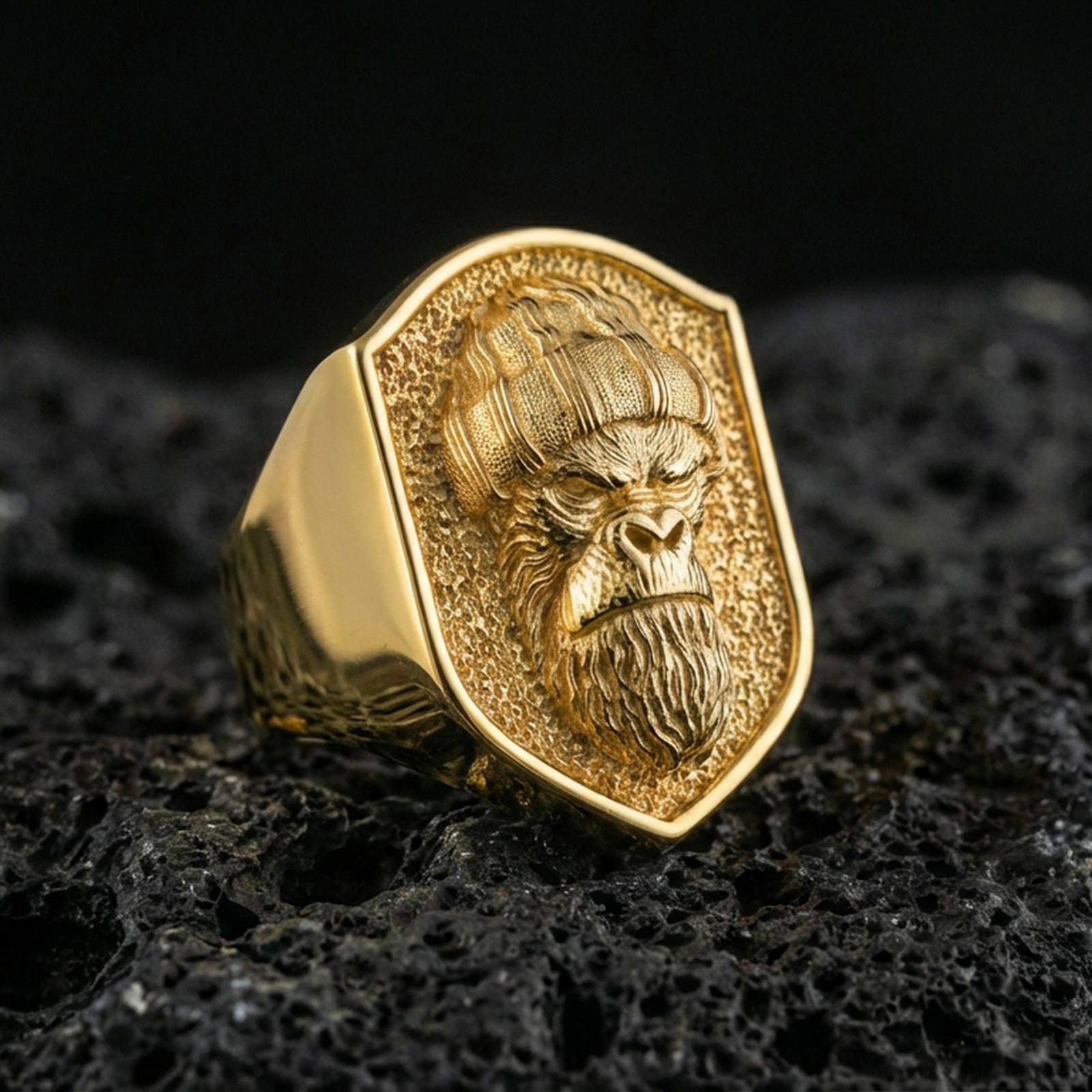 Gold plated gorilla warrior signet ring on volcanic rock, premium studio scene, bold warrior primate motif with sharp relief detail