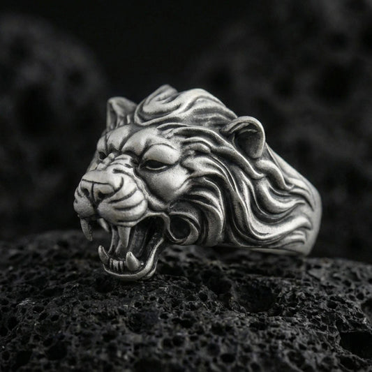 Oxidized sterling silver angry lion king ring on volcanic rock, roaring lion head with sculpted mane, macro studio close-up