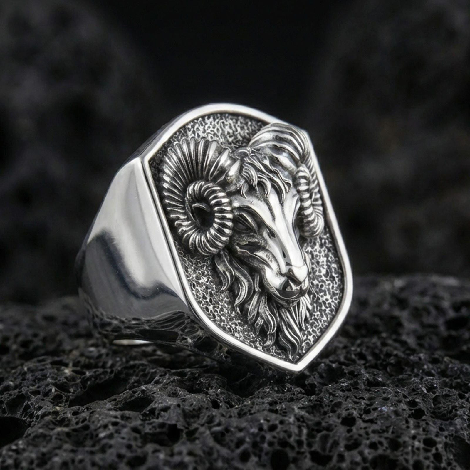 Polished silver ram head signet ring on volcanic rock, sharp horn detailing and sculpted fur lines, studio close-up
