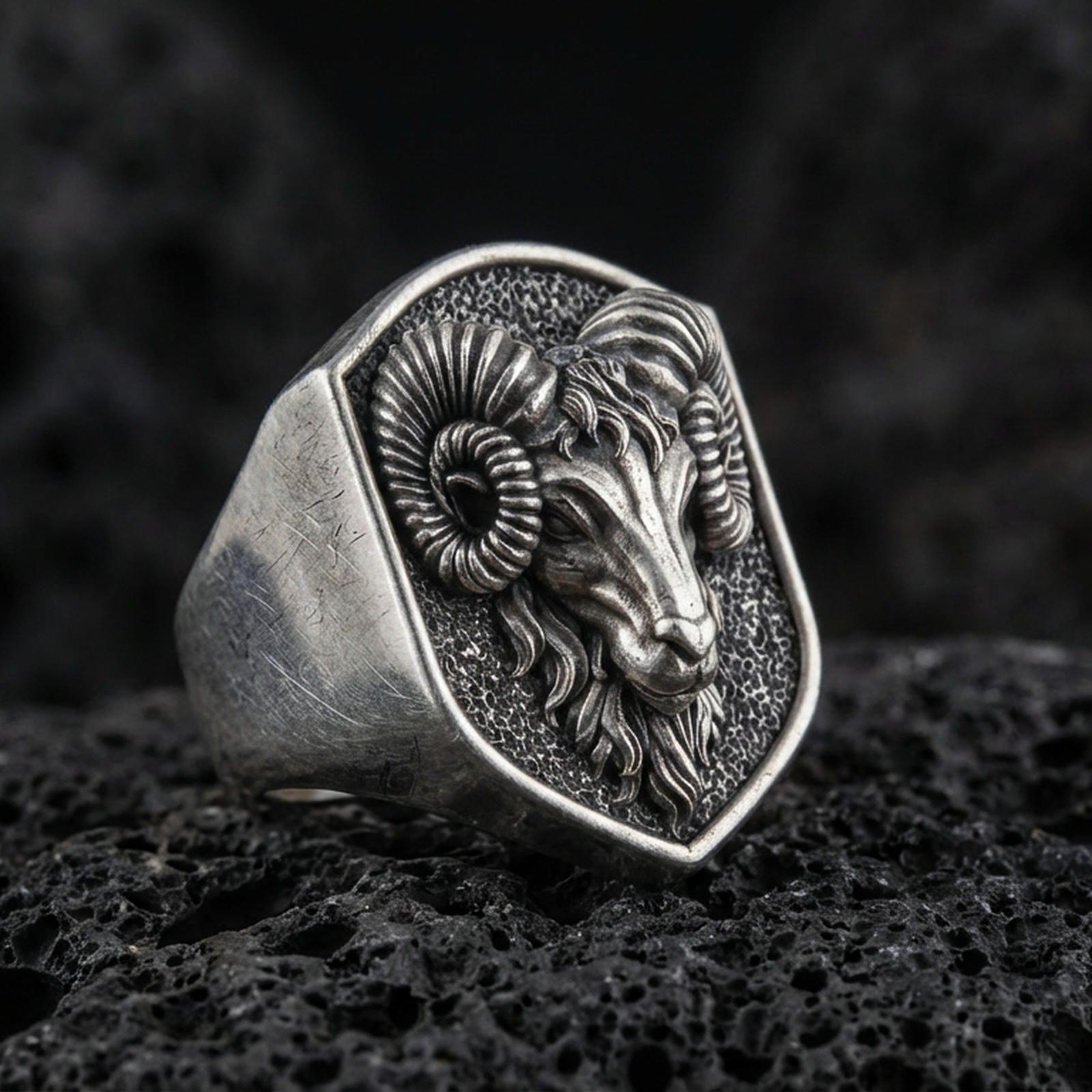 Oxidized sterling silver ram head signet ring on volcanic rock, curved horn relief and textured background, macro product shot