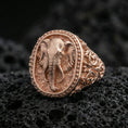 Load image into Gallery viewer, Rose gold plated elephant signet ring on volcanic rock, elephant head signet ring with textured relief and ornate swirl band, luxury close-up
