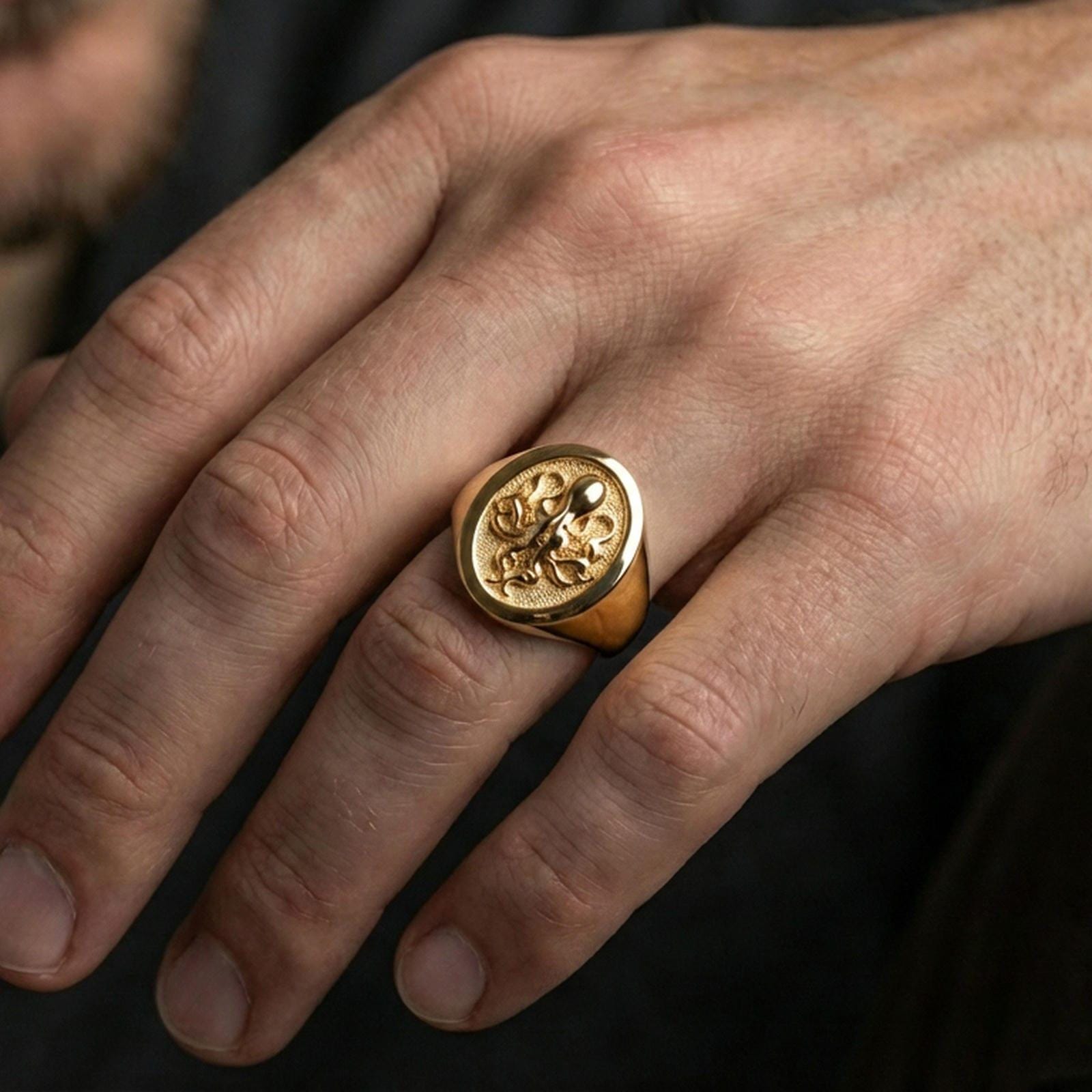 Gold plated octopus signet ring worn on finger, premium lifestyle photo, bold marine totem signet with crisp octopus motif