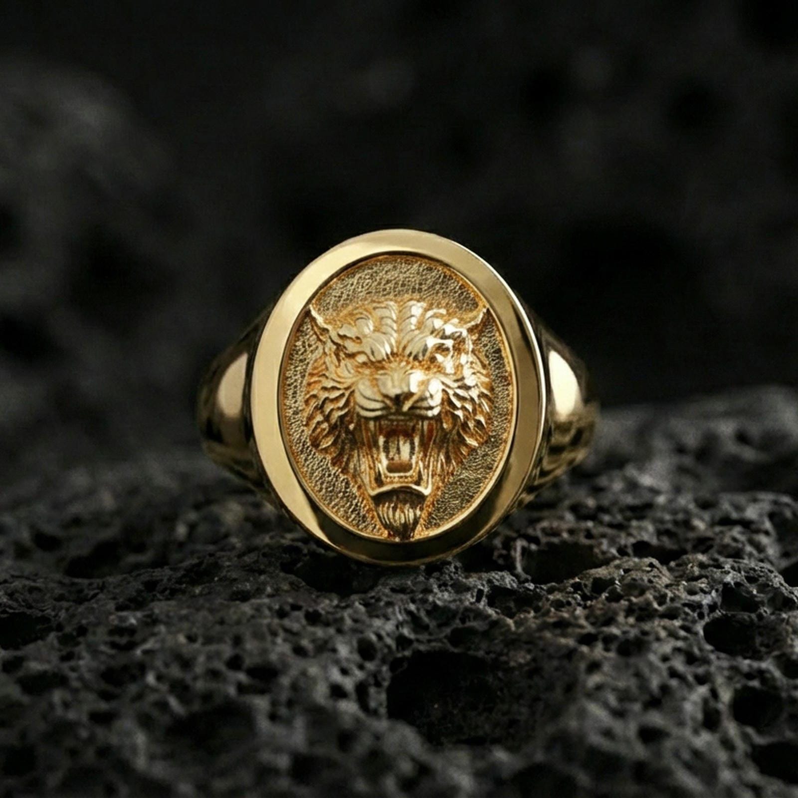 Gold plated tiger signet ring on volcanic rock, oval signet with fierce tiger head emblem and recessed textured field, premium studio lighting
