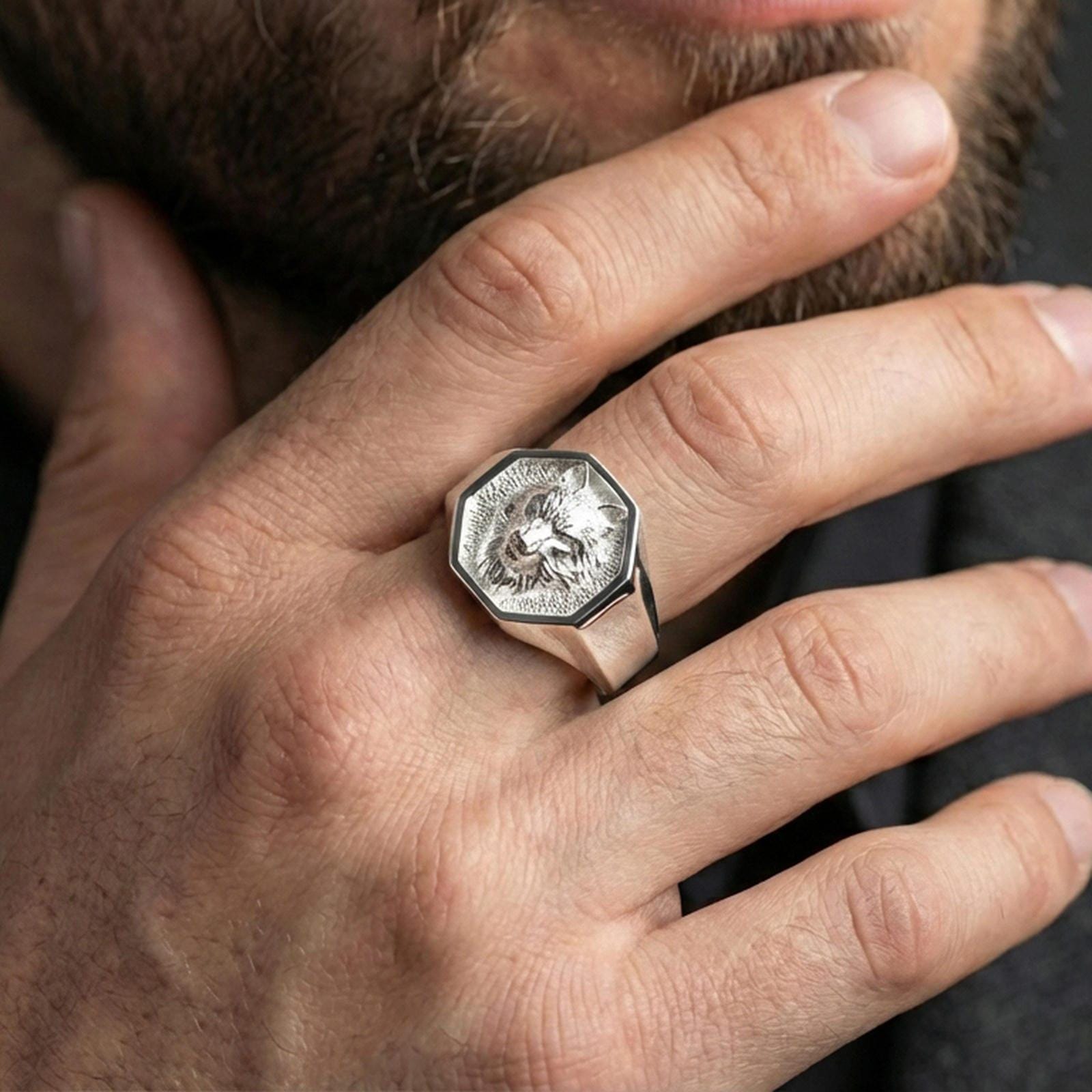 Polished silver wolf signet ring worn on finger, lifestyle hand shot, octagonal wolf emblem signet with crisp edge frame