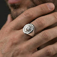 Load image into Gallery viewer, Polished silver oval wolf signet ring worn on finger, lifestyle hand shot highlighting crisp bezel edge and detailed wolf portrait
