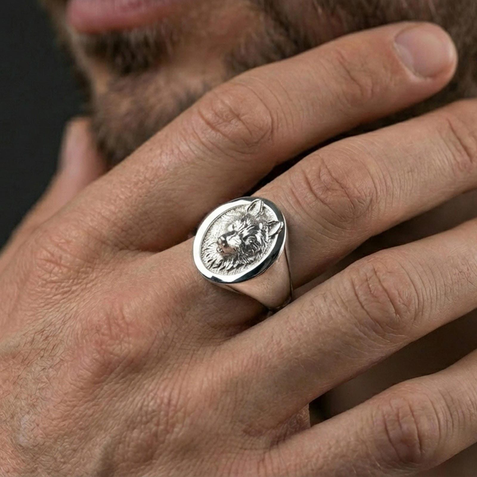 Polished silver oval wolf signet ring worn on finger, lifestyle hand shot highlighting crisp bezel edge and detailed wolf portrait