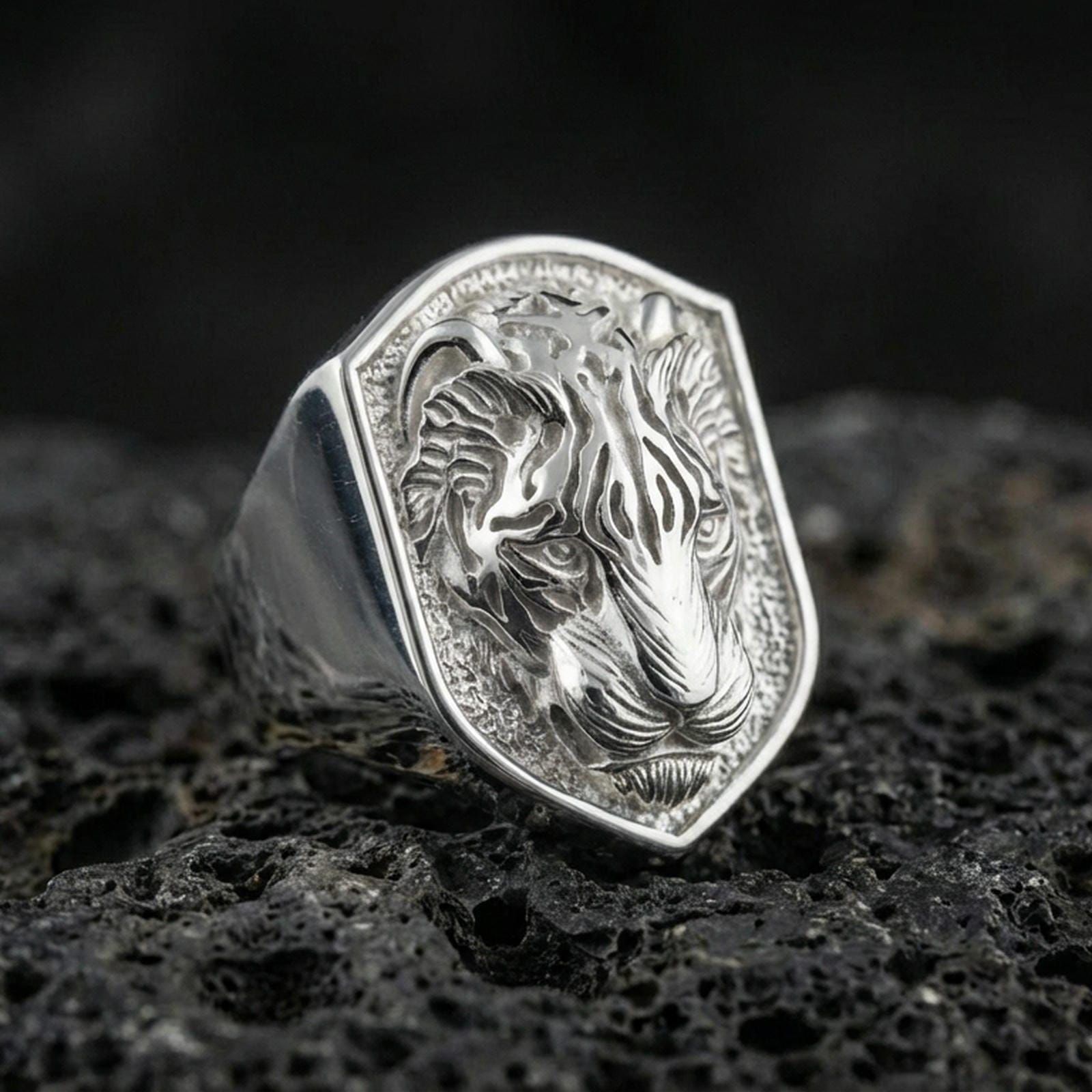 Polished silver tiger signet ring on volcanic rock, shield crest design with detailed tiger stripes and crisp beveled border, premium close-up shot